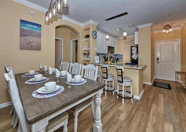 dining area with crown molding and light hardwood / wood-style floors