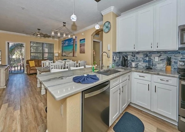 kitchen featuring kitchen peninsula, appliances with stainless steel finishes, white cabinetry, pendant lighting, and sink