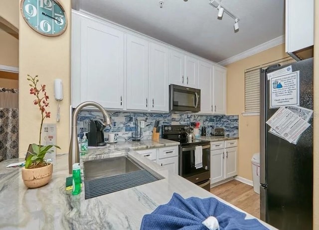 kitchen with crown molding, freestanding refrigerator, a sink, white cabinets, and electric stove