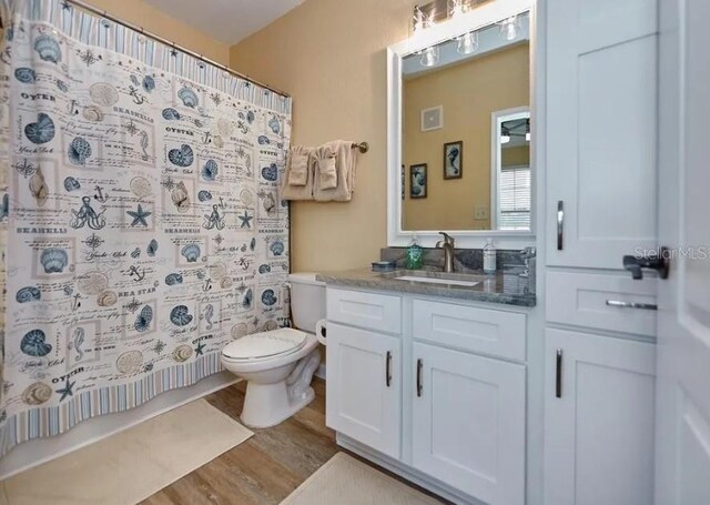 full bathroom with vanity, toilet, wood-type flooring, and shower / bathtub combination with curtain