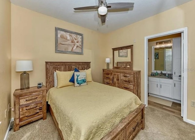 bedroom with a ceiling fan, light carpet, baseboards, connected bathroom, and a sink