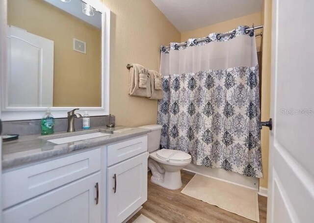 full bathroom with vanity, toilet, wood-type flooring, and shower / bath combo