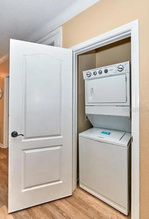 laundry room featuring laundry area, stacked washing maching and dryer, and light wood-type flooring