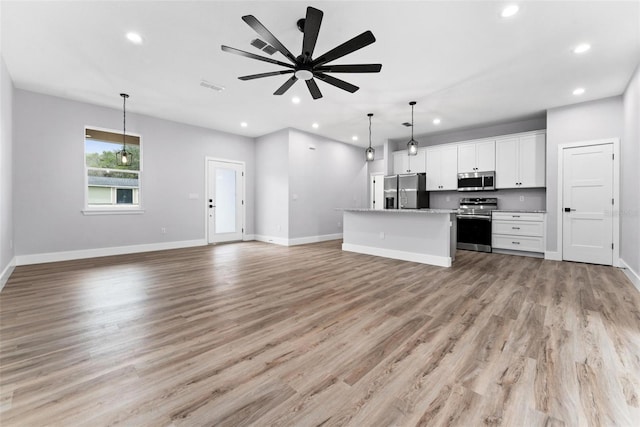 kitchen with a kitchen island, light hardwood / wood-style floors, stainless steel appliances, pendant lighting, and white cabinets