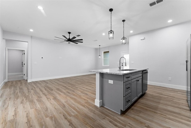 kitchen featuring a kitchen island with sink, light hardwood / wood-style flooring, stainless steel dishwasher, sink, and gray cabinets