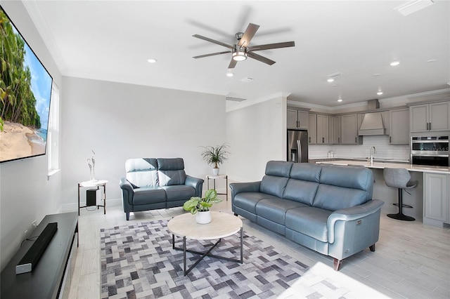 living room with sink, ceiling fan, ornamental molding, and light hardwood / wood-style flooring