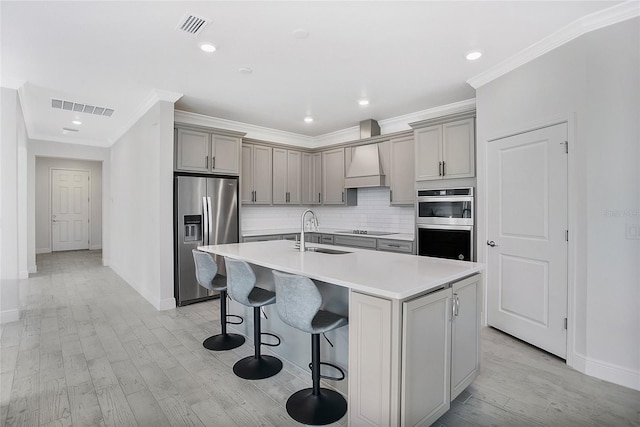 kitchen featuring a center island with sink, premium range hood, light wood-type flooring, stainless steel refrigerator with ice dispenser, and sink