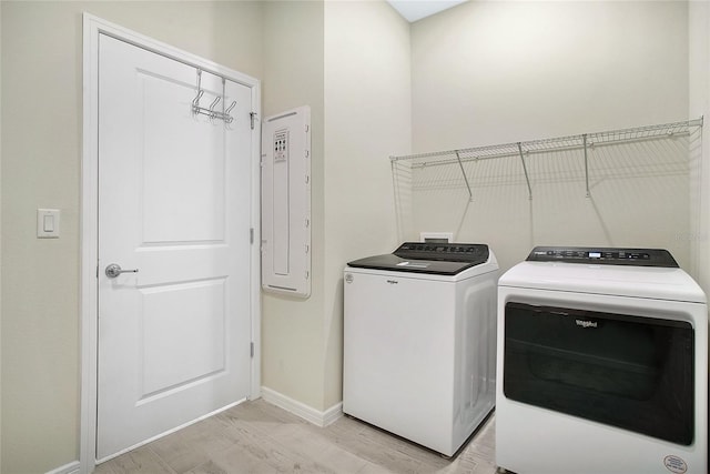 washroom featuring light hardwood / wood-style flooring, washer and dryer, and electric panel