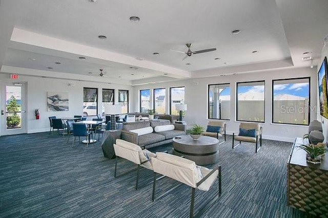 carpeted living room with ceiling fan, a tray ceiling, and a wealth of natural light