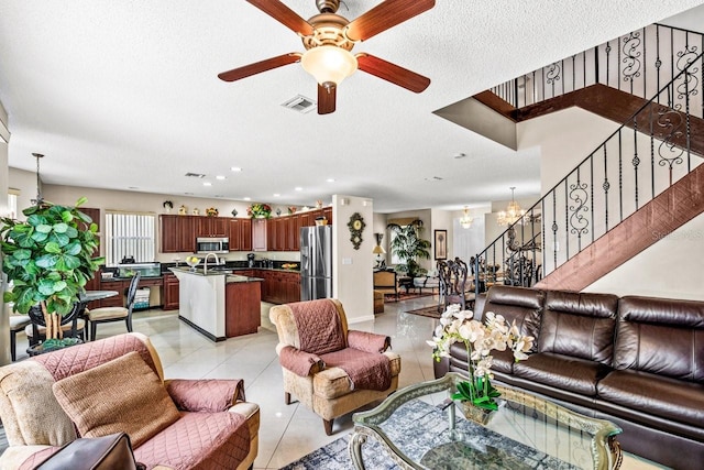 tiled living room featuring a textured ceiling and ceiling fan with notable chandelier