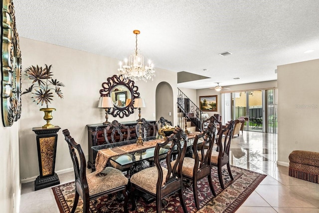 tiled dining area featuring a textured ceiling and ceiling fan with notable chandelier