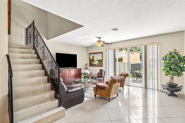 living room with ceiling fan, a textured ceiling, and light tile patterned floors