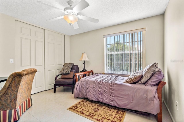 tiled bedroom with a closet, a textured ceiling, and ceiling fan