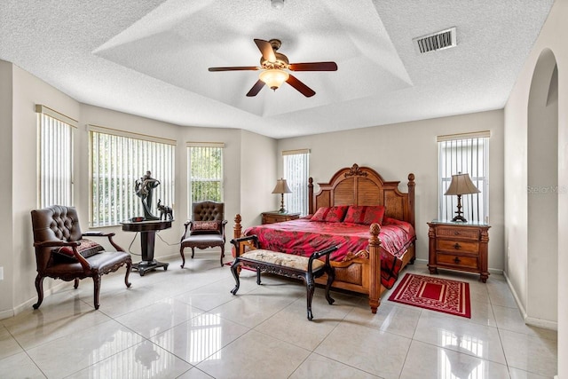 bedroom with a raised ceiling, a textured ceiling, and ceiling fan