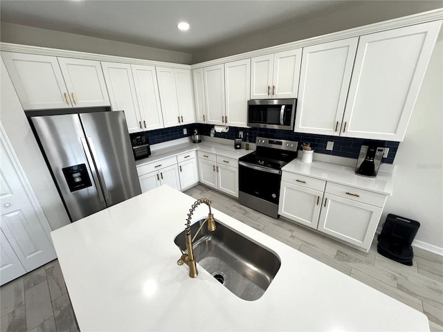 kitchen with backsplash, sink, white cabinets, light wood-type flooring, and appliances with stainless steel finishes