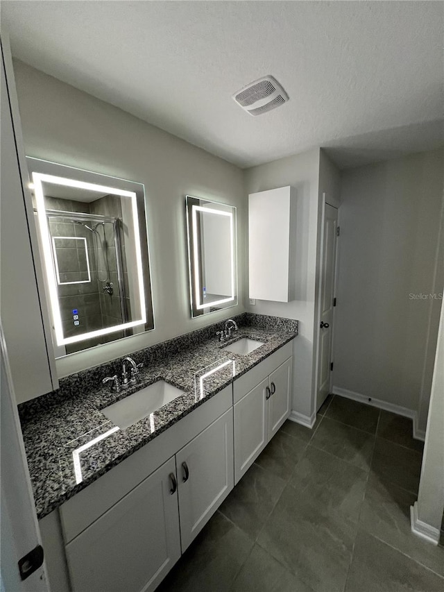 bathroom featuring vanity, an enclosed shower, a textured ceiling, and tile patterned flooring