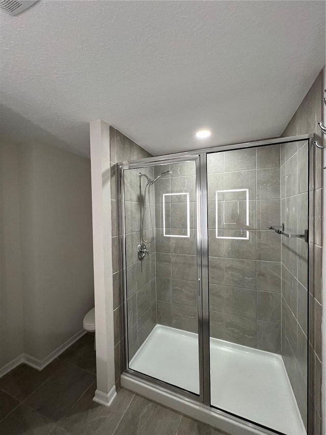 bathroom with a shower with door, tile patterned floors, a textured ceiling, and toilet