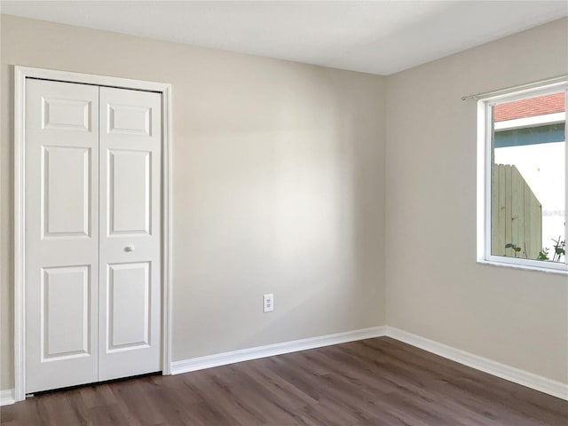 unfurnished bedroom with dark hardwood / wood-style floors and a closet