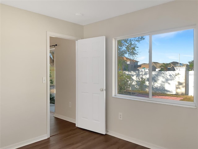 unfurnished bedroom featuring multiple windows and dark wood-type flooring