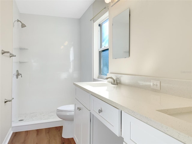 bathroom with vanity, toilet, tiled shower, and hardwood / wood-style floors