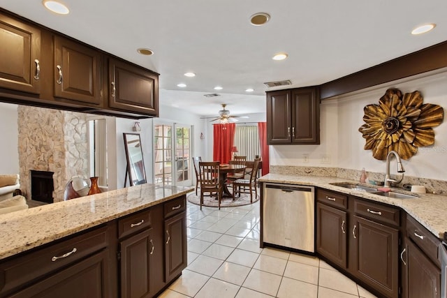 kitchen featuring sink, dishwasher, a stone fireplace, ceiling fan, and dark brown cabinetry