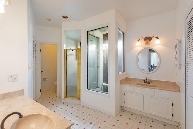 bathroom featuring toilet, a shower with shower door, and vanity