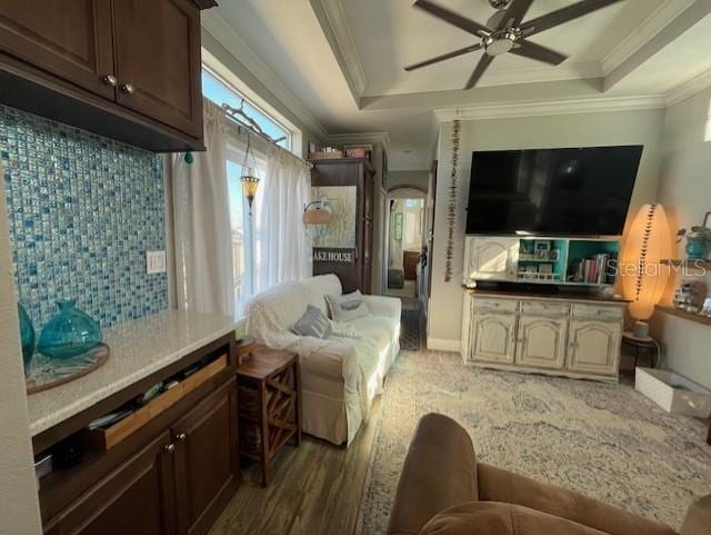 living room featuring crown molding, a tray ceiling, dark hardwood / wood-style floors, and ceiling fan