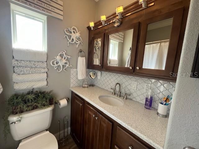 bathroom with vanity, tasteful backsplash, and toilet