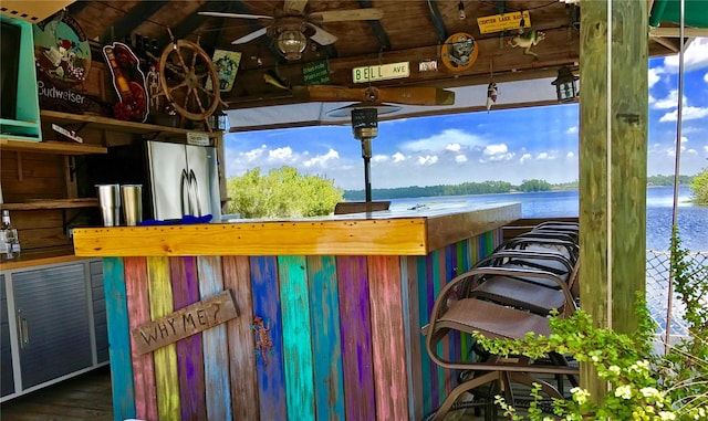 exterior space with exterior bar, a water view, and ceiling fan