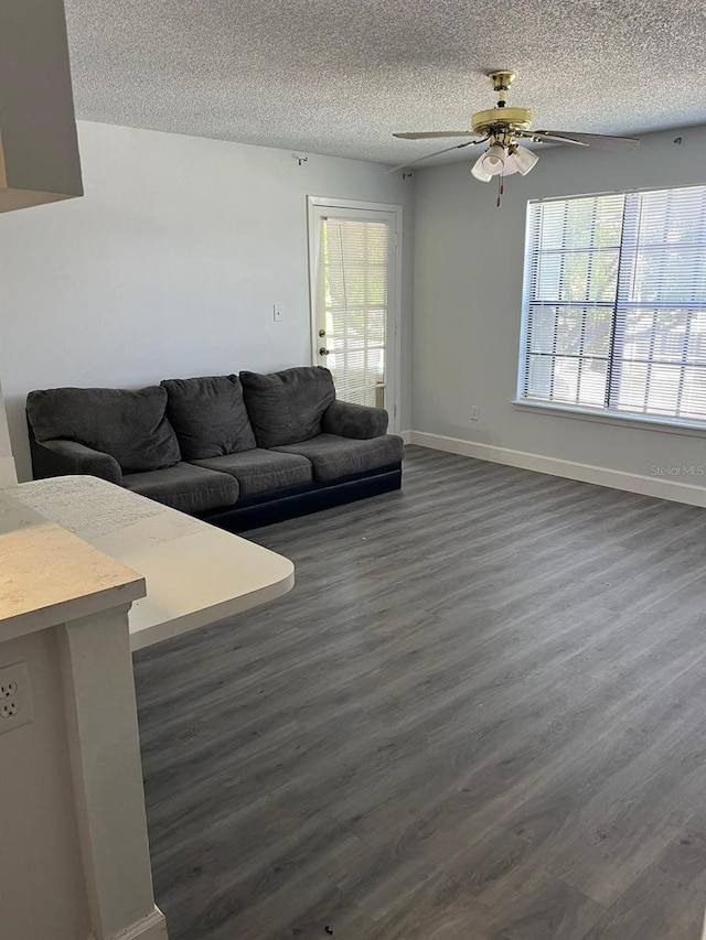 living room with a textured ceiling, dark wood-type flooring, and a healthy amount of sunlight