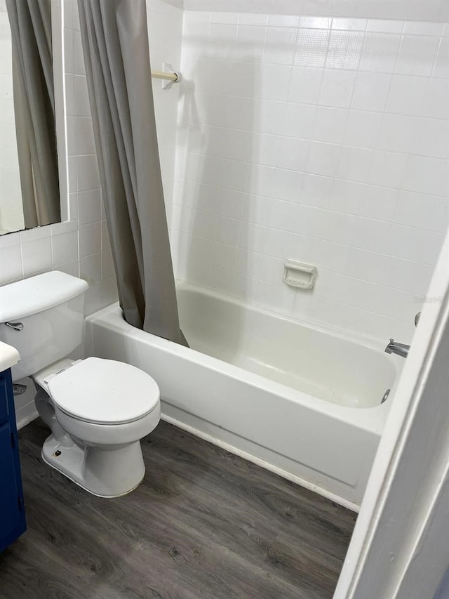 full bathroom featuring wood-type flooring, shower / bath combination with curtain, toilet, and vanity