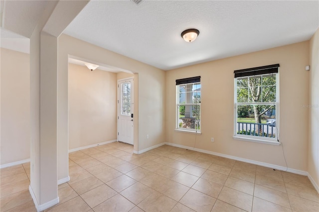 spare room with a textured ceiling and light tile patterned floors