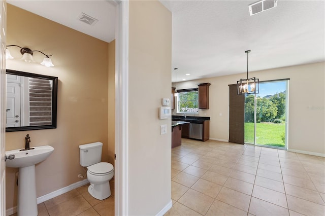 bathroom with sink, toilet, a chandelier, and tile patterned flooring