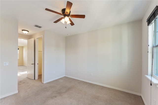 carpeted empty room featuring ceiling fan and plenty of natural light