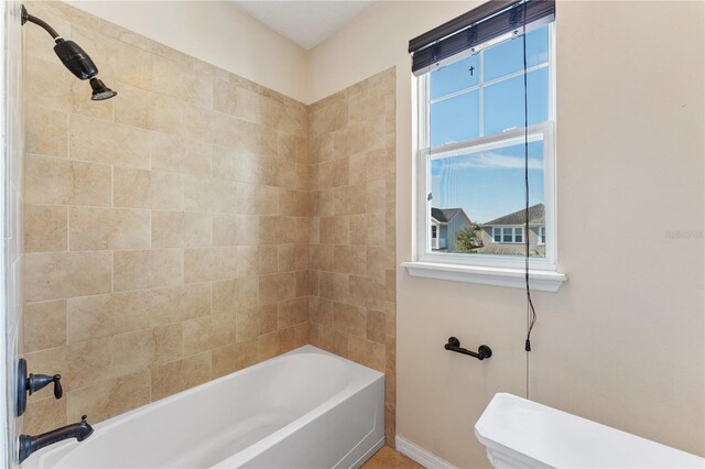 bathroom featuring tiled shower / bath and toilet