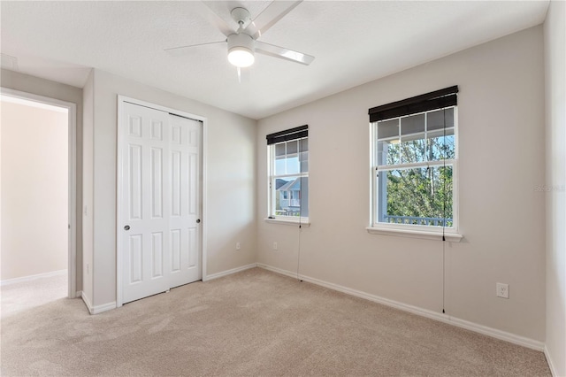 unfurnished bedroom with light carpet, a closet, and ceiling fan