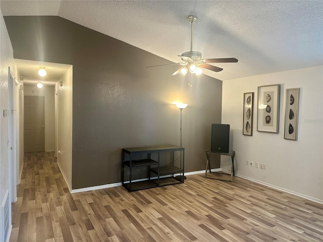 interior space featuring light hardwood / wood-style floors, a textured ceiling, vaulted ceiling, and ceiling fan