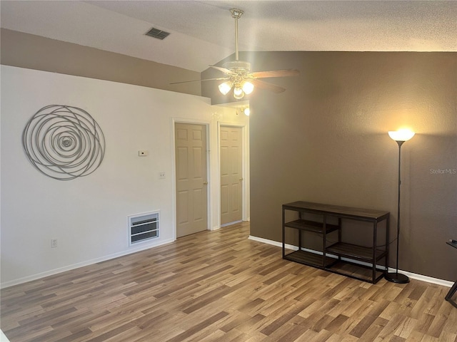 unfurnished room featuring ceiling fan, a textured ceiling, wood-type flooring, and lofted ceiling