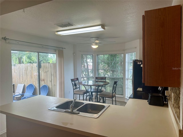 kitchen with kitchen peninsula, a textured ceiling, sink, and ceiling fan