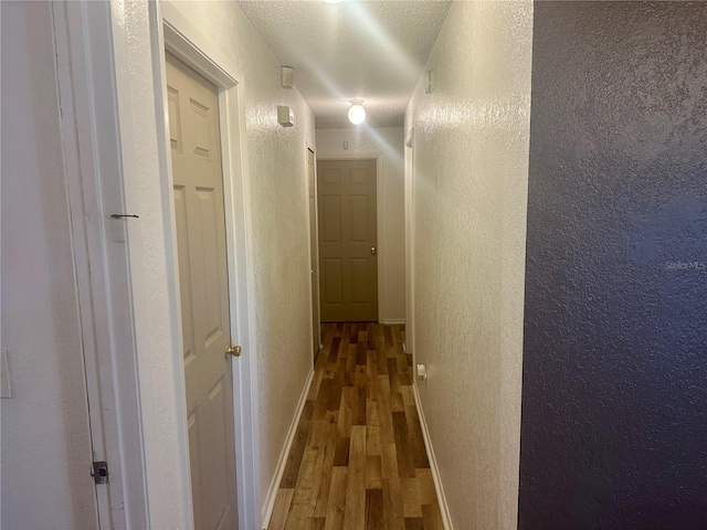 hall featuring a textured ceiling and wood-type flooring