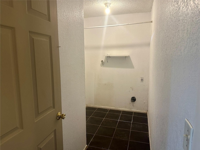 washroom with a textured ceiling and dark tile patterned floors