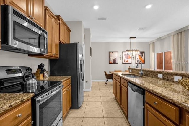 kitchen with sink, light tile patterned flooring, stainless steel appliances, dark stone counters, and a notable chandelier