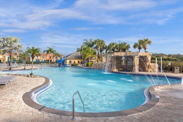 view of swimming pool featuring a patio, a water slide, and pool water feature