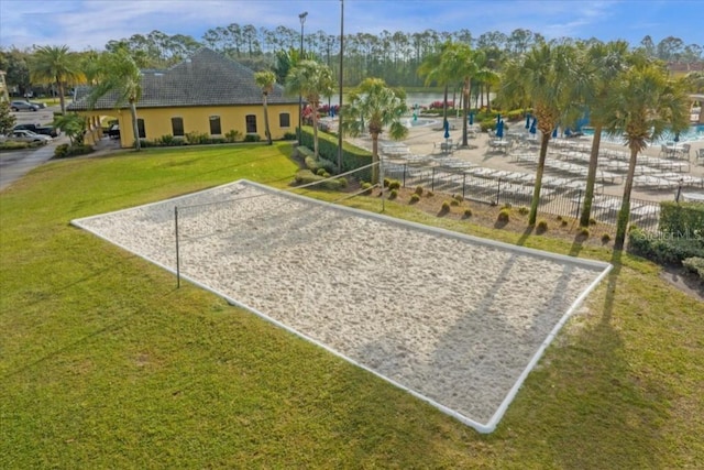 surrounding community featuring a water view, a lawn, and volleyball court