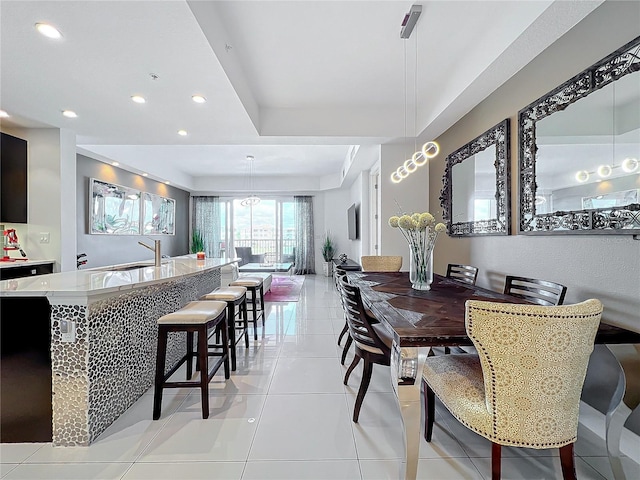 tiled dining area with sink and a tray ceiling