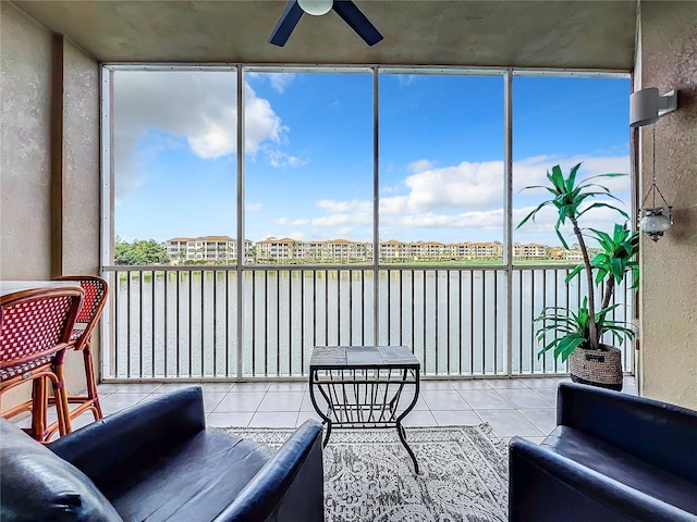 sunroom featuring ceiling fan and a water view