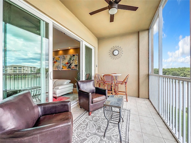 sunroom with ceiling fan and a water view