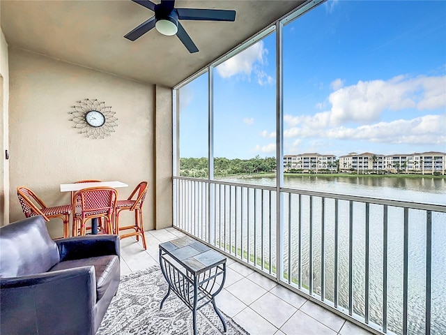 sunroom with ceiling fan and a water view