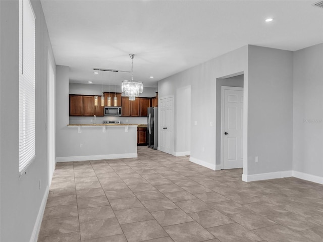 kitchen with open floor plan, stainless steel appliances, light countertops, a chandelier, and pendant lighting