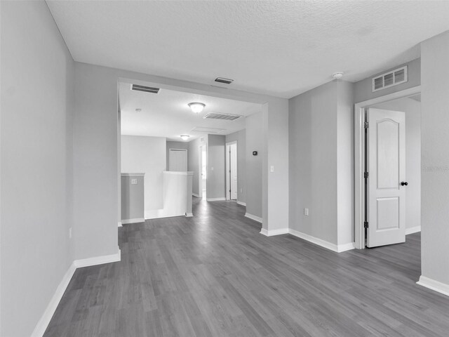 unfurnished room with baseboards, visible vents, and dark wood-style flooring